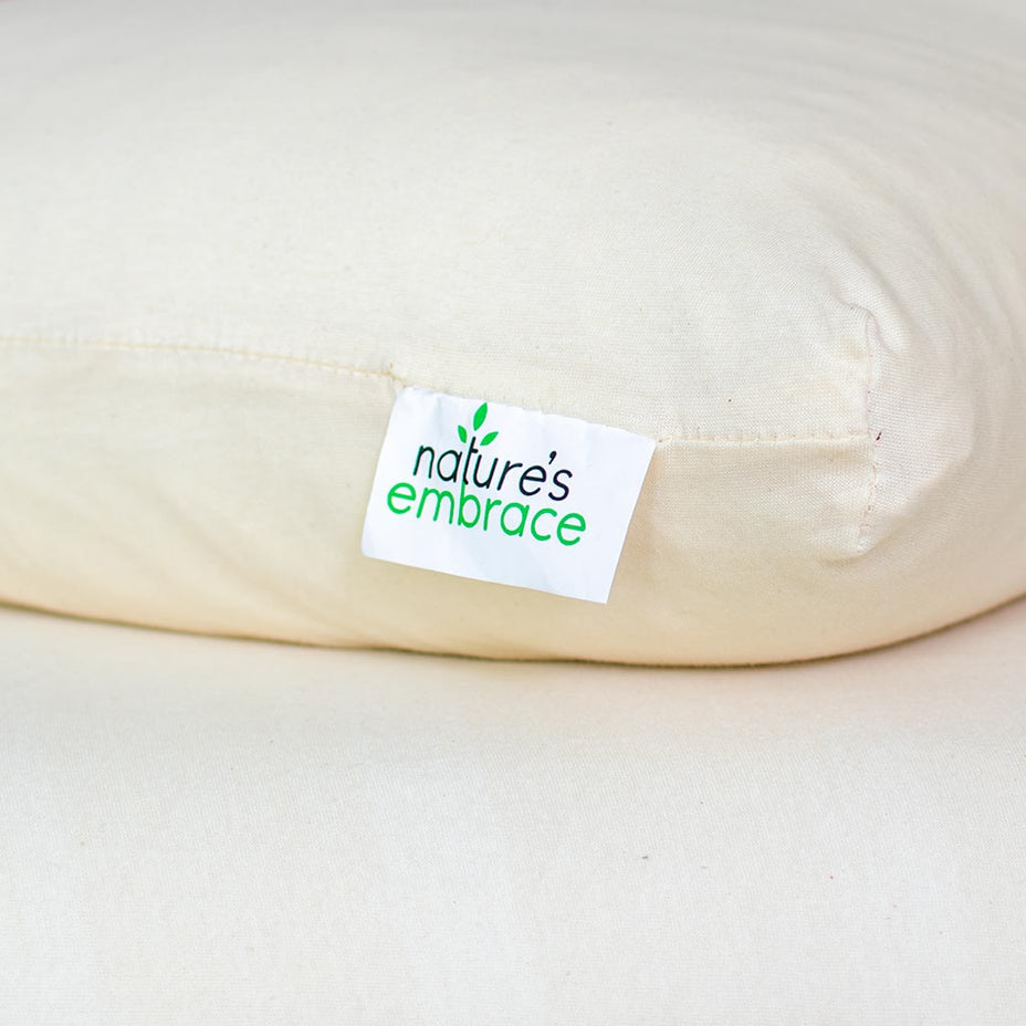 Close-up of a 'nature's embrace' label on a beige pillow.